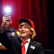 A man dressed like Republican presidential candidate Donald Trump takes a photo of himself before Trump arrives at a campaign event (Associated Press)